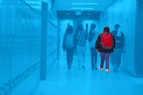 Students walking in a hallway with one standing out in full color.