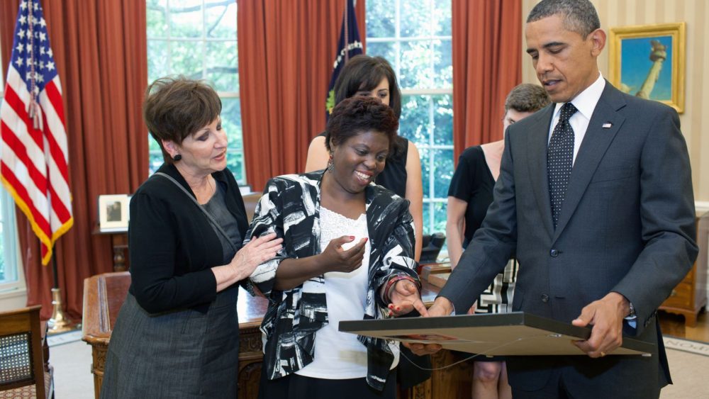 Lois Curtis hands a painting to President Barack Obama in the Oval Office